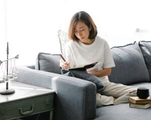 woman sitting on a couch writing in her gratitude journal