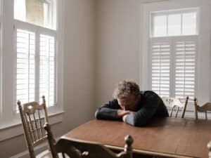distraught man sitting at the kitchen table attempting to detox at home from alcohol