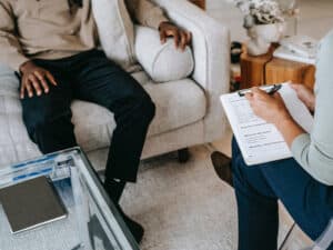 man sitting on a couch with his therapist discussing dual diagnosis